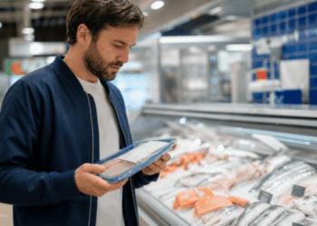 Consumer choosing between wild and farmed fish at a seafood counter