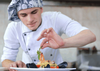 Chef al lavoro nella preparazione di un piatto di pesce in una cucina professionale