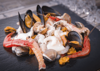 Selezione di crostacei e frutti di mare su piatto nero per Ittica Sud