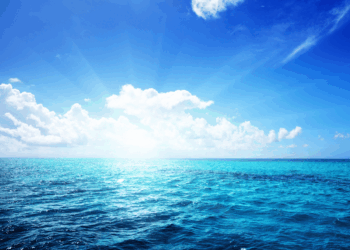 Superficie del mare sotto un cielo azzurro con nuvole all’orizzonte