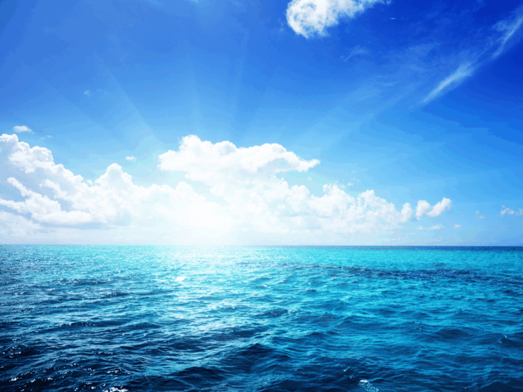 Superficie del mare sotto un cielo azzurro con nuvole all’orizzonte